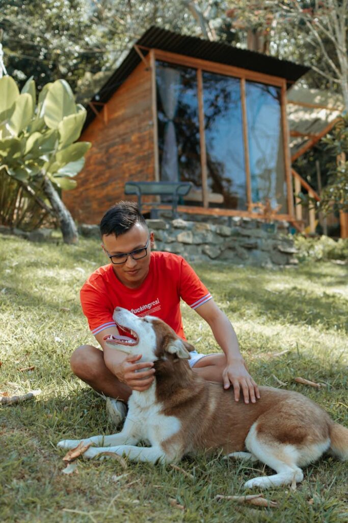 Services 3 A man in a red shirt lovingly pets a dog in a lush garden setting.